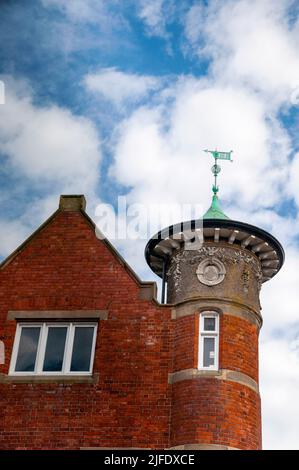 Portrush in Nordirland Ziegelfassade mit einer grünen Windfahne auf einem viktorianischen Turm. Stockfoto