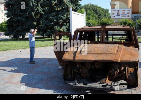 Ein Mann inspiziert den verbrannten Panzerwagen Tiger der Russischen Föderation, der sich auf dem Maidan Nezalezhnosti in der Nähe des Schewtschenko-Denkmals befindet. Stockfoto