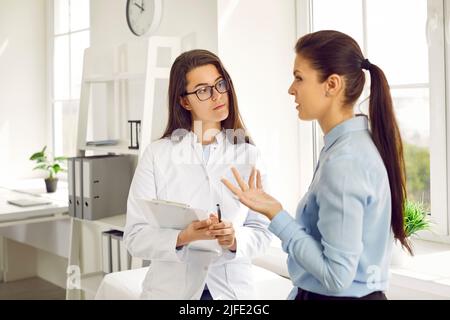 Junge kaukasische Frau in Krankenschwester Mantel arbeitet als Arzt in Kosmetologie Klinik hört auf weibliche Patientin Stockfoto