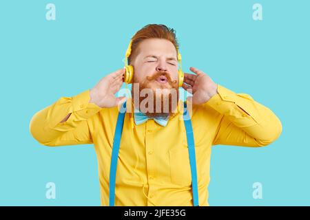 Lustiger, fröhlicher, molliger bärtiger Mann, der mitsingt, während er in Kopfhörern Musik hört Stockfoto