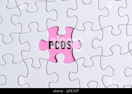 PCOS-Text auf weißem Puzzle auf rosa Hintergrund. Polyzystisches Eierstock-Syndrom Gesundheitskonzept. Stockfoto