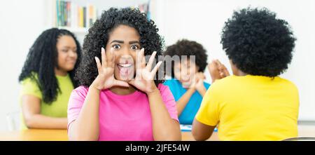 Glückliche brasilianische Studentin mit einer Gruppe afroamerikanischer junger Erwachsener im Klassenzimmer der Hochschule Stockfoto