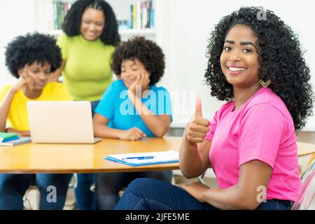 Erfolgreicher afroamerikanischer Informatikstudent mit einer Gruppe codierender Studenten an der Universität Stockfoto