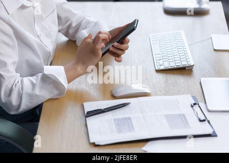Nahaufnahme von weiblichen Händen, die das Telefon benutzen, Geschäftsfrau bei der Arbeit. Stockfoto