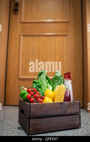 Food-Shopping-Box stehen vor der Tür des Hauses oder der Wohnung. Gemüse- und Obstlieferung während Quarantäne und Selbstisolation Stockfoto