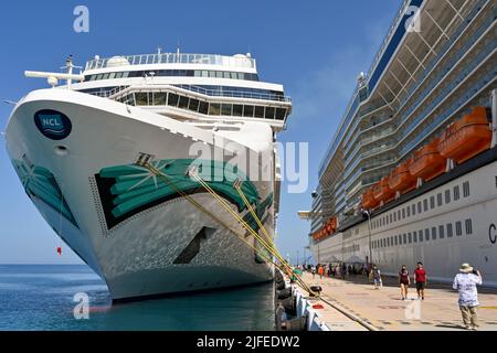 Kusadasi, Türkei - Juni Mai 2022: Passagiere, die zwischen zwei Kreuzfahrtschiffen im Hafen laufen. Auf der linken Seite befindet sich das norwegische Jade-Kreuzschiff Stockfoto