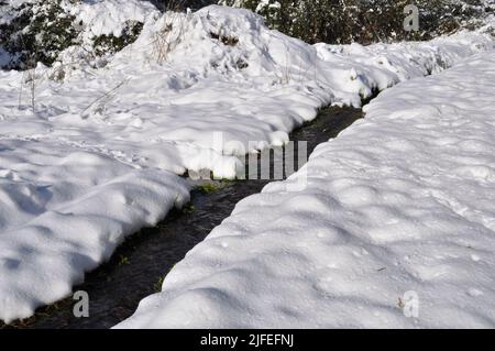 Wasserlauf im Schnee in der Bretagne Stockfoto