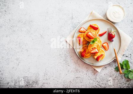 Quark-Pfannkuchen, Ricotta-Fritten oder Syrniki mit Minze und Erdbeeren. Gesundes und leckeres Frühstück am Morgen Stockfoto