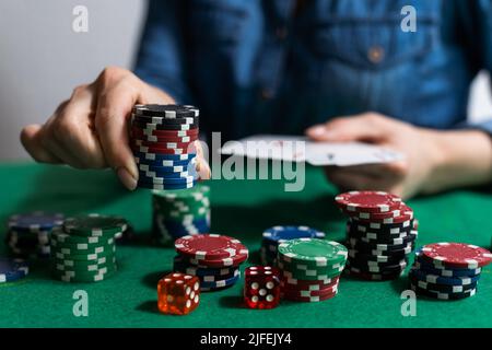 Eine Frau spielt in einem Casino. Öffnen von Karten, um Wetten zu erhöhen. Vor dem Hintergrund von Chips. Poker-Sieg Stockfoto