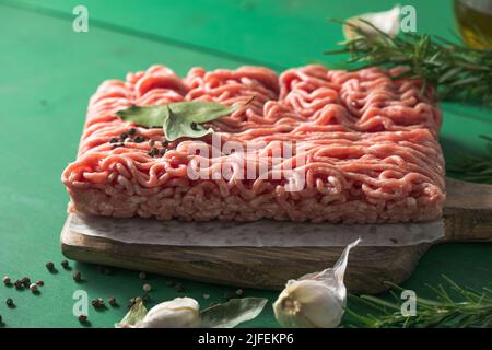 Rohes Hackfleisch, Hackfleisch aus Hackfleisch auf einem Schneidebrett. Grüner Hintergrund. Draufsicht Stockfoto