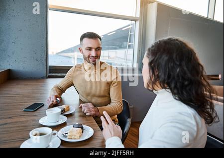 Charmantes kaukasisches liebendes Paar auf Hochzeitsreise, Naschen zusammen in der Cafeteria des internationalen Flughafen-Abflugterminals und warten auf den Brauch Stockfoto