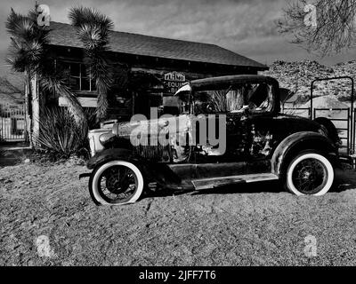 Eine Graustufenaufnahme eines alten rostigen Ford auf der Route 66 Stockfoto