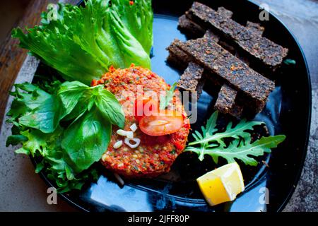 Köstlicher Avocado-, Mango- und roher Lachssalat, Tartare, serviert auf einem weißen Teller mit Limette. Das Konzept der gesunden Ernährung, vegetarische Ernährung, festliche Snack Stockfoto