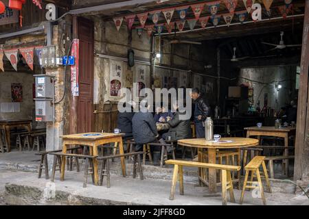 Eine Straßenansicht einer Gruppe asiatischer Menschen, die in einem Teehaus in China Karten spielen Stockfoto