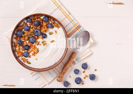 Blick von oben auf Vanillejoghurt und Heidelbeeren auf einer weißen Holzoberfläche; Platz zum Kopieren Stockfoto