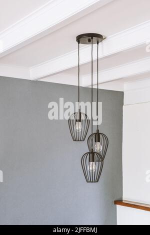 Eleganter schwarzer Kronleuchter im Loft-Stil in einem Raum mit grauen Wänden und einer weißen Balkendecke Stockfoto