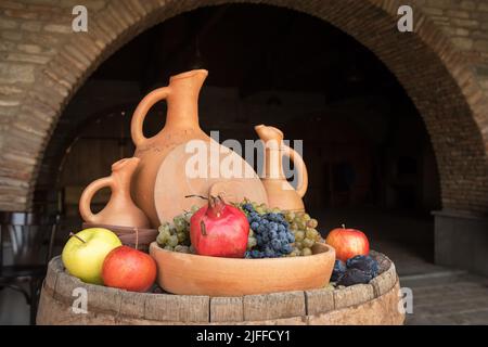 Servierfass mit Tonkrügen und Früchten in der Weinkellerei in Georgia Stockfoto