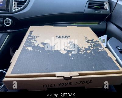 Seattle, WA USA - ca. Mai 2022: Nahaufnahme einer Zeeks Pizzabox im Schoß einer Person in einem Auto. Stockfoto
