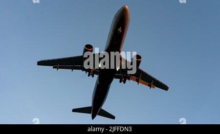 Die Silhouette eines Passagierflugzeugs, das vor dem Hintergrund des Sonnenuntergangs landet. Stockfoto