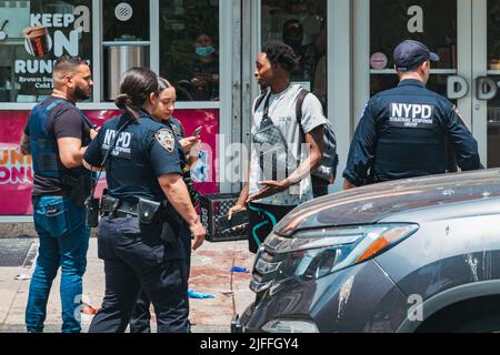 2. Juli 2022: NYPD-Offiziere sprechen mit einem Mann vor der Szene einer Schießerei in Manhattans Lower East Side, New York Stockfoto