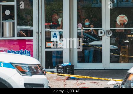 2. Juli 2022: Mitarbeiter von Dunkin' Donuts schauen aus dem Schaufenster, nachdem vor ihr in Manhattans Lower East Side, New York, ein Mann geschossen wurde Stockfoto