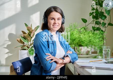 Porträt einer jungen lächelnden Frau in Kopfhörern, die auf die Kamera schaut Stockfoto
