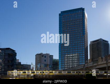 Ein Zug der Serie E231-500 auf der Chuo-Soba-Linie fährt vor hohen Gebäuden in Iidabashi, Tokio, Japan. Stockfoto