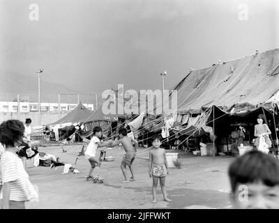 Das vietnamesische Untersuchungsgefängnis Shek Kong wurde 1989 in wenigen Wochen am westlichen Ende der Militärpiste in Shek Kong, New Territories, Hongkong, errichtet. Auf der Start- und Landebahn wurden Zelte aufgestellt, und das Gras auf beiden Seiten wurde von einem Metallzaun umgeben, der von Stacheldraht gekrönt wurde. Zehntausende vietnamesische Asylbewerber sind in den Jahren der Operation Photo, die im Dezember 1990 aufgenommen wurde, durch das Lager gegangen. Stockfoto