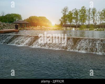 Landschaftsgestaltung im Hausgarten, schöne Landschaftsgestaltung mit Teich und Wasserfall. Landschaftlich gestalteter Platz mit Steinen und Wasser am Landhaus. Schöner Teich und Stockfoto