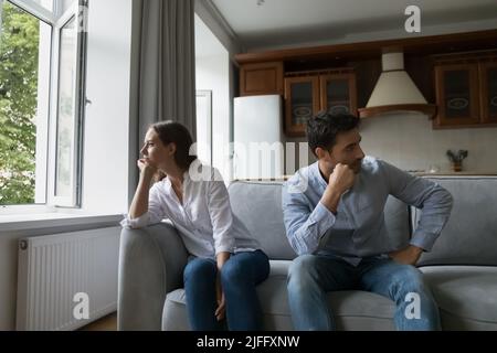 Trauriges junges Paar sitzt nach einem Streit auseinander auf dem Sofa Stockfoto