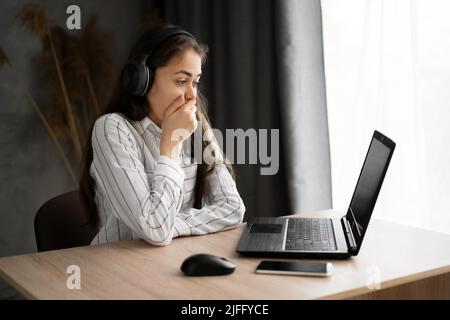 Junge hispanische Frau, die einen beängstigenden Film sieht, sich vor Angst versteckt, Online-Film-Service Stockfoto