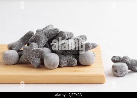 Salzige Lakritze salmiakki auf dem hölzernen Schneidebrett mit dem Kopieplatz Stockfoto