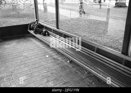 Obdachlos in den 1950s. Ein Mann wird auf der Bank an einer Bushaltestelle geschlafen dargestellt. Schweden 1954 Kristoffersson Ref. 2A-27 Stockfoto