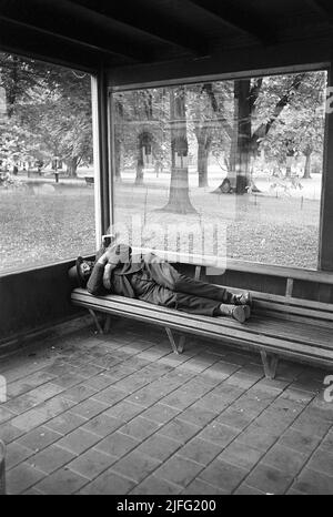 Obdachlos in den 1950s. Ein Mann wird auf der Bank an einer Bushaltestelle geschlafen dargestellt. Schweden 1954 Kristoffersson Ref. 2A-27 Stockfoto