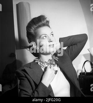 Einkaufen in der 1940s. Schauspielerin Greta Gynt, 1916-2000 im Laden Svenskt Tenn in Stockholm hat sich gezeigt, wie sie eine Halskette ausprobieren kann, wenn sie zu ihr passt. Der Laden ist hoch spezialisiert und berühmt für seine Kollektionen von dekorativem Design und Schmuck, die sie selbst produzieren und Importe aus der ganzen Welt. Svenskt Tenn ist immer noch im Geschäft (2022) Schweden 1946 Ref X122-5 Stockfoto