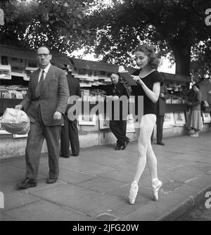 Ballerina in Paris 1952. Ellen rasch, 1920-2015 in Paris im Tanzkostüm, das auf ihren Zehen steht und ein Buch von einem Straßenhändler-Stand liest. Paris 1952 Kristoffersson Ref. BD27-7 Stockfoto
