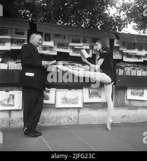 Ballerina in Paris 1952. Ellen rasch, 1920-2015, in Paris in ihrem Tanzkostüm, auf einer Zehe stehend und vor einem Straßenhändler-Stand ein Buch liest. Paris 1952 Kristoffersson Ref. BD27-5 Stockfoto