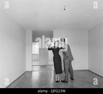 In der 1950s. Ein junges Paar, das in ihrer neuen Wohnung abgebildet ist. Sie ist kreativ und positiv mit Ideen, wie man dekorieren. Seine Körpersprache deutet darauf hin, dass er zurückhaltender und nicht so spontan ist. Schweden 1957. Stockfoto