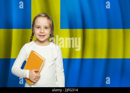 Mädchen mit Buch steht vor schwedischer Flagge Hintergrund. Schule und Bildung in Schweden Konzept Stockfoto