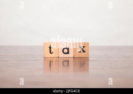 Steuer. Steuerzeichen. Geschrieben in Kleinbuchstaben auf einem Holzblock. Geschrieben auf drei Blöcken auf einem Holztisch gestapelt. Stockfoto