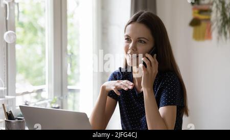 Glückliche freiberufliche Mitarbeiterin, die im Heimbüro einen Anruf entgegennimmt Stockfoto