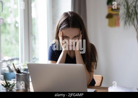 Gestresst schockierte junge Frau frustriert über Probleme mit Laptop Stockfoto