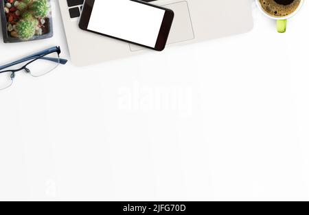 Weißer Büroschreibtisch mit Laptop-Computer, Smartphone und Brille, flaches Lay. Draufsicht mit Kopierbereich (selektiver Fokus). Büroschreibtisch-Konzept. Stockfoto