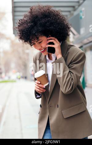 Lächelnde junge lateinerin, die am Telefon spricht Stockfoto