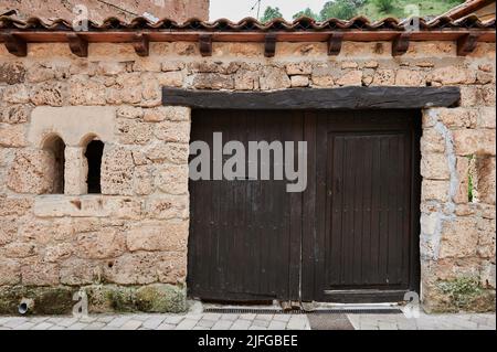 Steinfassade mit kleiner alter Holztür in der kleinen Stadt Orbaneja del Castillo, Burgos, Spanien, Europa Stockfoto