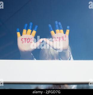 Kinderhände auf Glas Fenster, in gelb-blauer Farbe gemalt, Inschrift in rot STOPPEN KRIEG. Russlands Invasion der Ukraine, Kinder gegen Krieg. Bleib Stockfoto