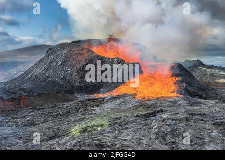 Lavafontänen aus dem Vulkankrater in Island. Landschaft auf der Halbinsel Reykjanes im Frühling mit Sonnenschein. Flüssige Lava fließt aus der Seite Stockfoto