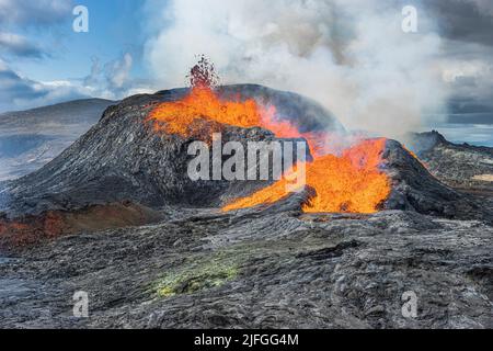 Aktiver Vulkan auf der isländischen Halbinsel Reykjanes. Kleiner Lavafontäne aus dem Krater. Landschaft im Frühling mit Sonnenschein. Flüssige Lava fließt aus dem Stockfoto