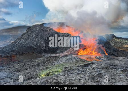 Vulkanausbruch auf der isländischen Halbinsel Reykjanes. Aktiver Vulkan mit Lavafontäne. Seitlicher Ausfluss der heißen rötlichen Lava. Blick auf den Vulkan im Stockfoto