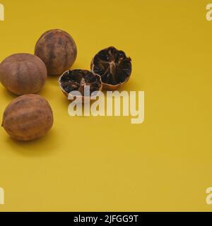 Sonnengetrocknete Bio-Loomi oder Black Lime, Black Lemon, Omani Lemon Früchte auf gelbem Hintergrund. Küche des Nahen Ostens Stockfoto